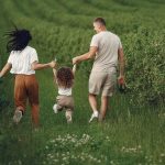 A joyful family strolls through a lush green field, enjoying quality time together.