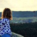 A little girl that is standing on a rock